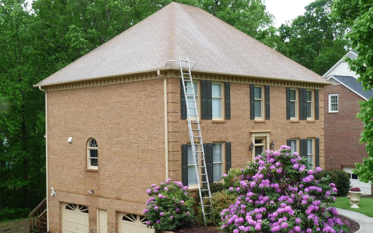 A brick home with a clean shingle roof after our softwash roof treatment