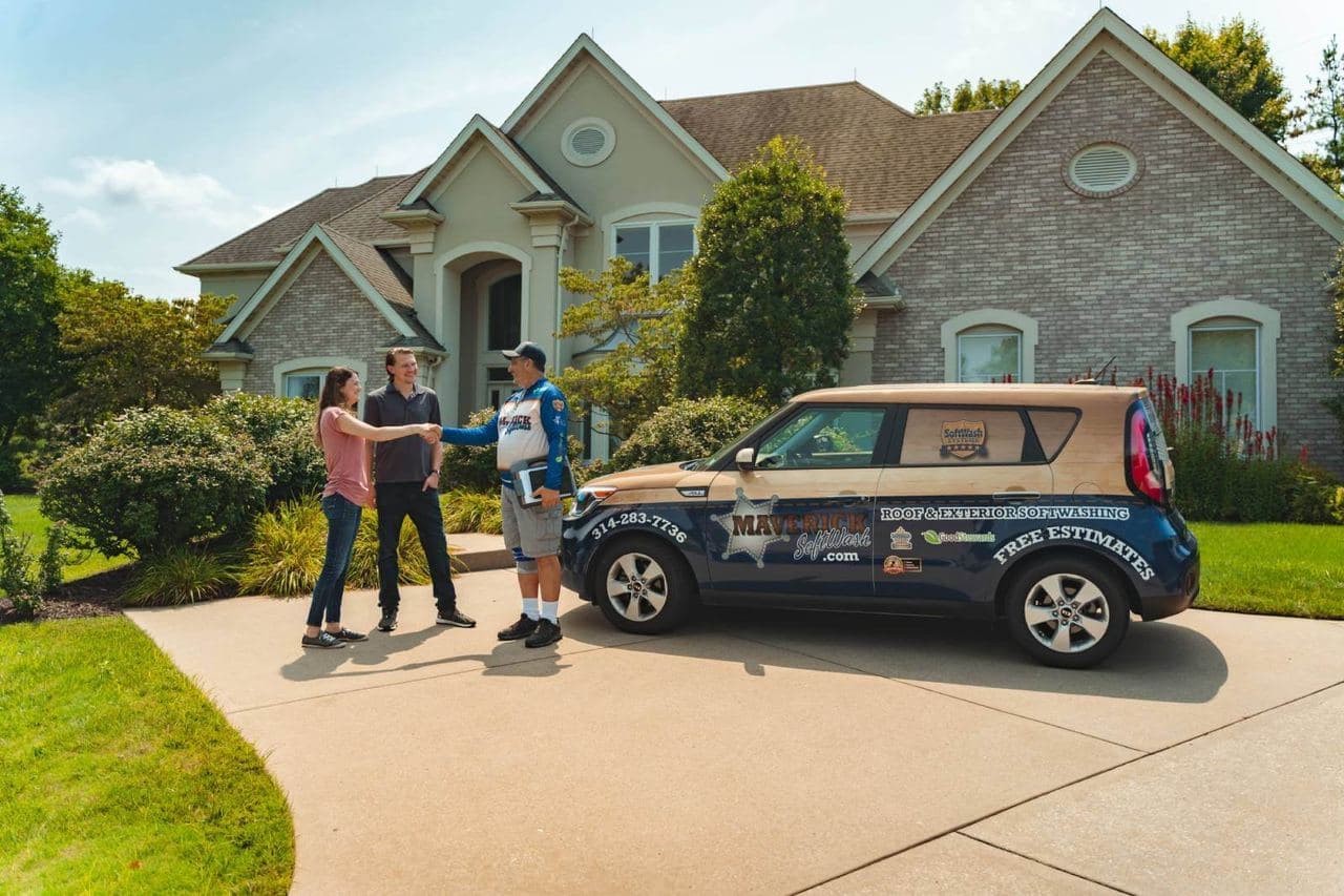 A Maverick SoftWash technician greeting two people in a driveway next to a branded company vehicle